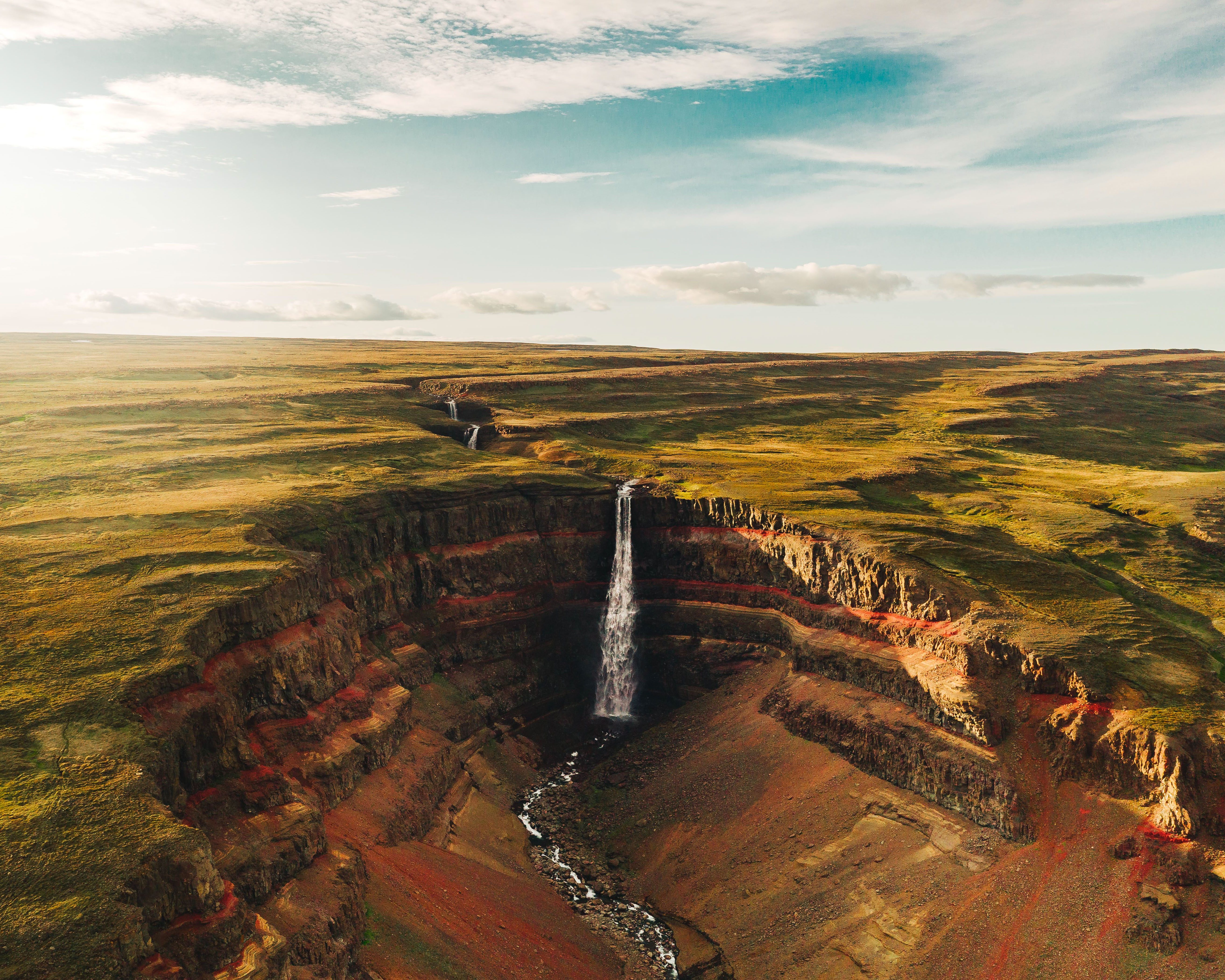 The dramatic basalt columns and red clay layers of Hengifoss waterfall in East Iceland.